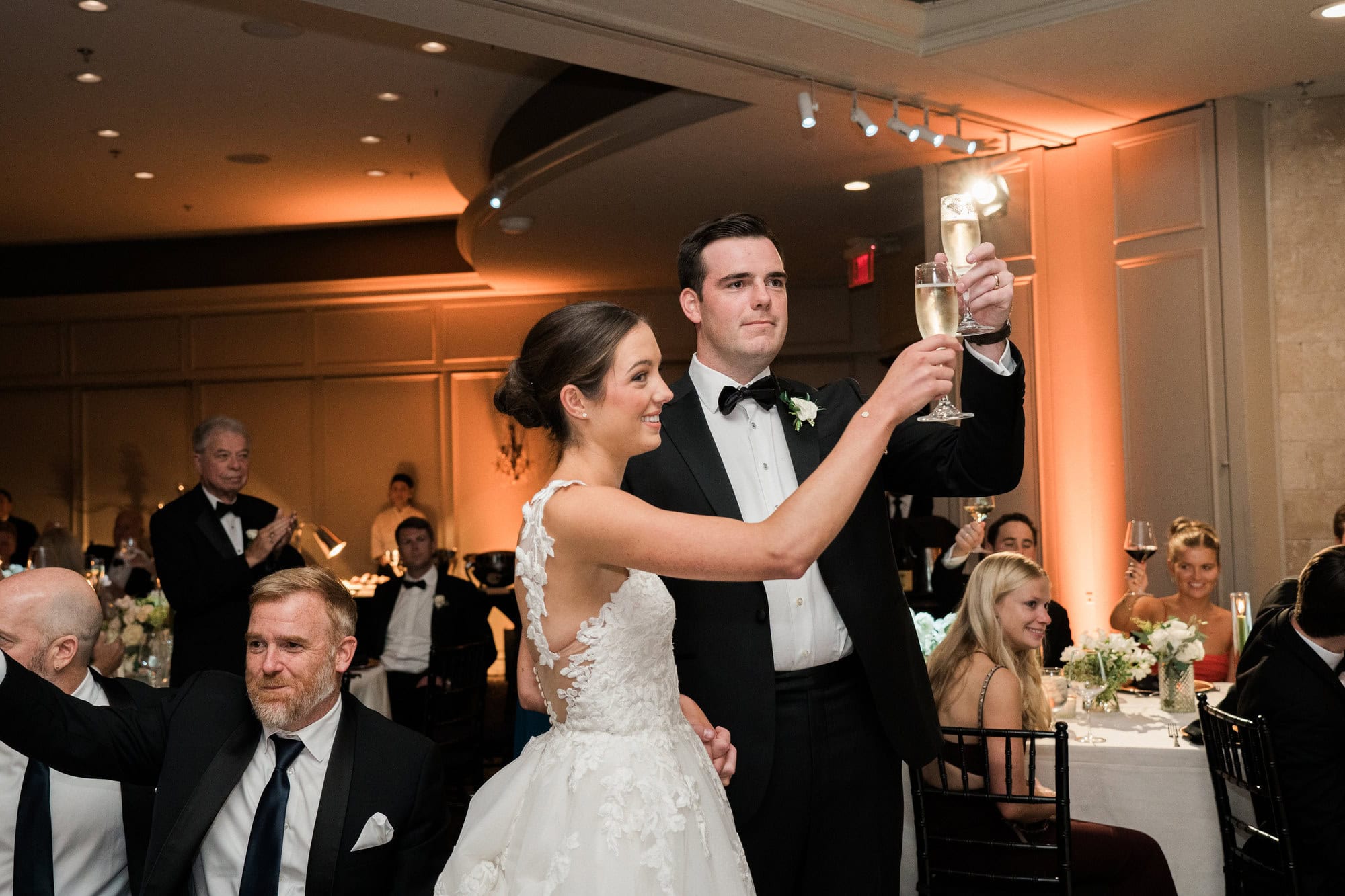 Sydney and Cade raising champagne glasses during their reception.