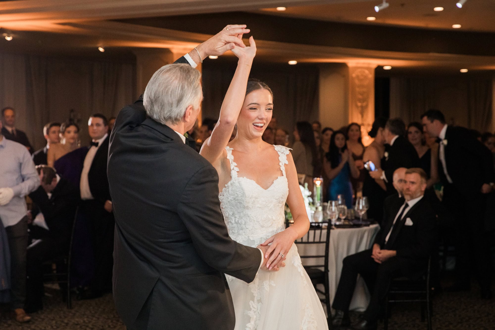 Sydney smiling as her dance partner twirls her at the reception.