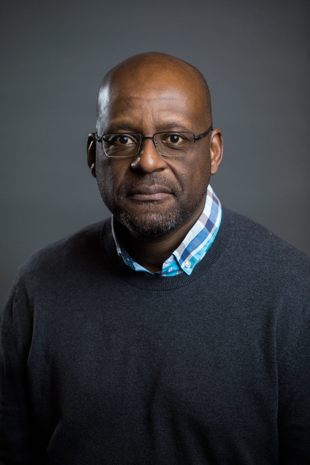 Corporate headshot photographer Houston: man in glasses and a gray sweater