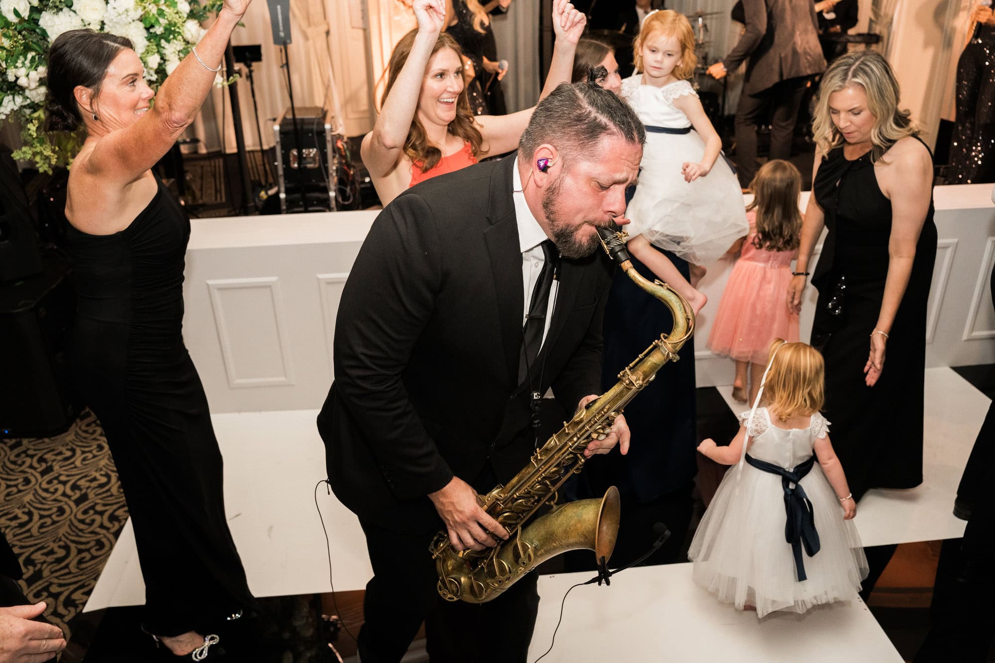 Saxophonist playing among guests on the wedding dance floor.
