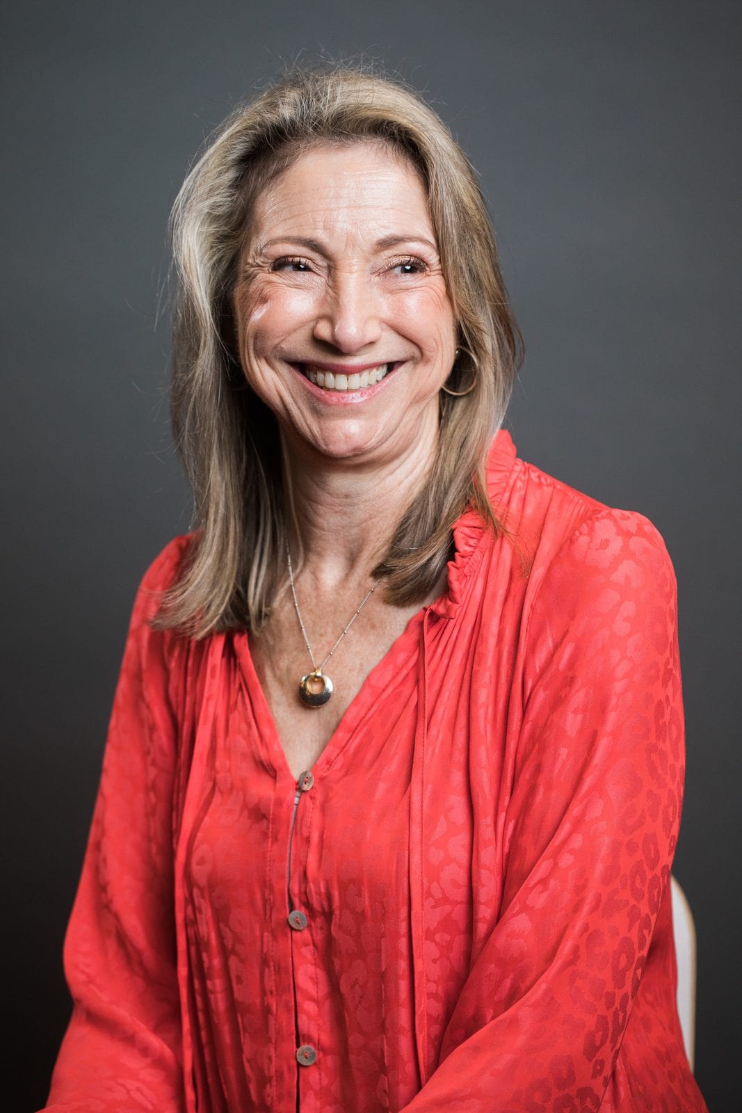 LinkedIn headshots Houston: smiling woman in a coral blouse