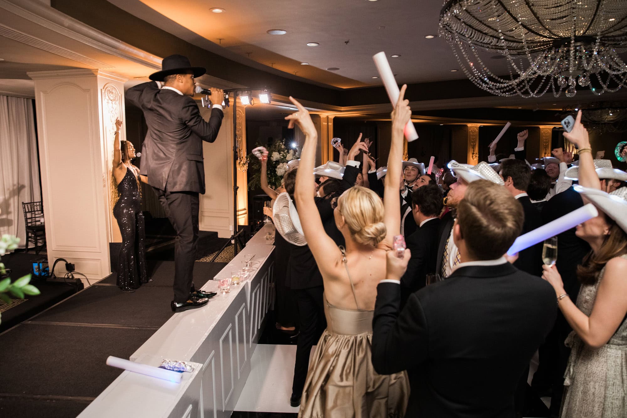 Live singer performing for wedding guests with raised party wands.