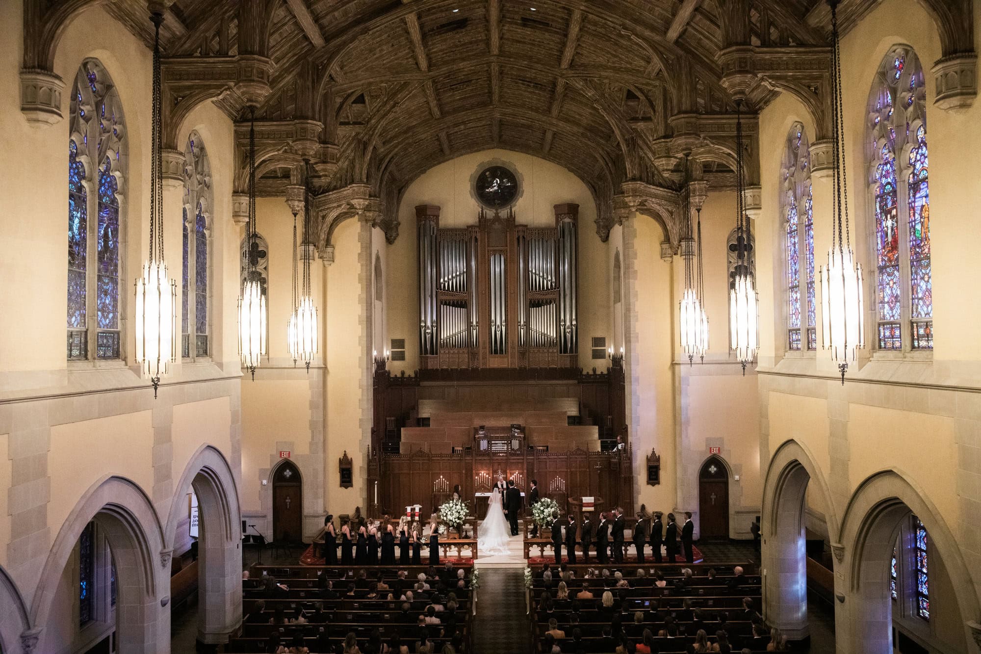 Wide view of Sydney and Cade’s wedding ceremony beneath the vaulted church ceiling.