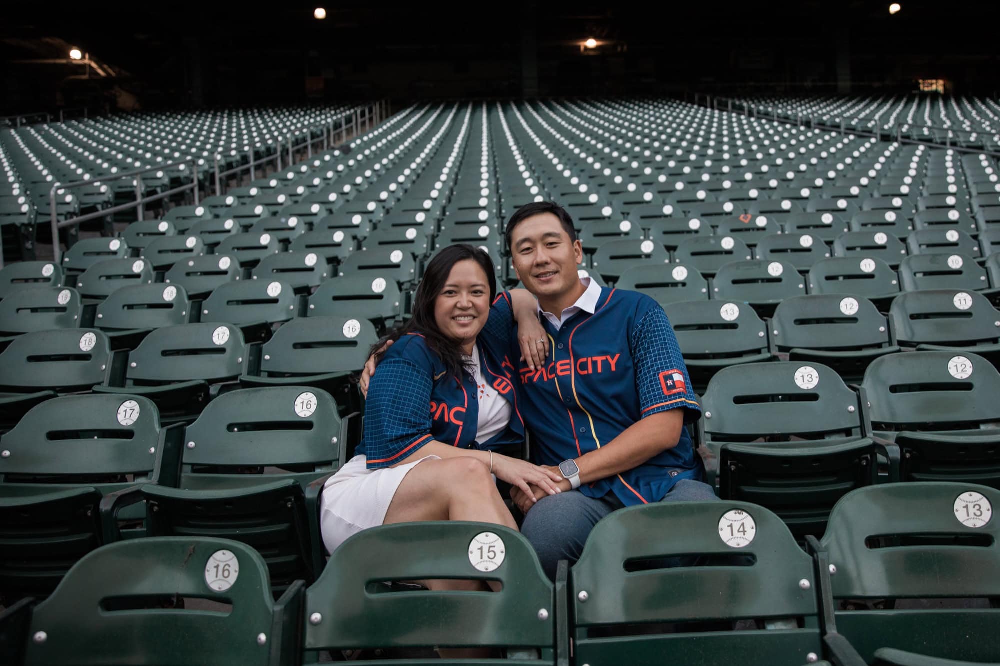when should you take engagement photos Engaged couple wearing matching baseball jerseys while seated in a Houston stadium